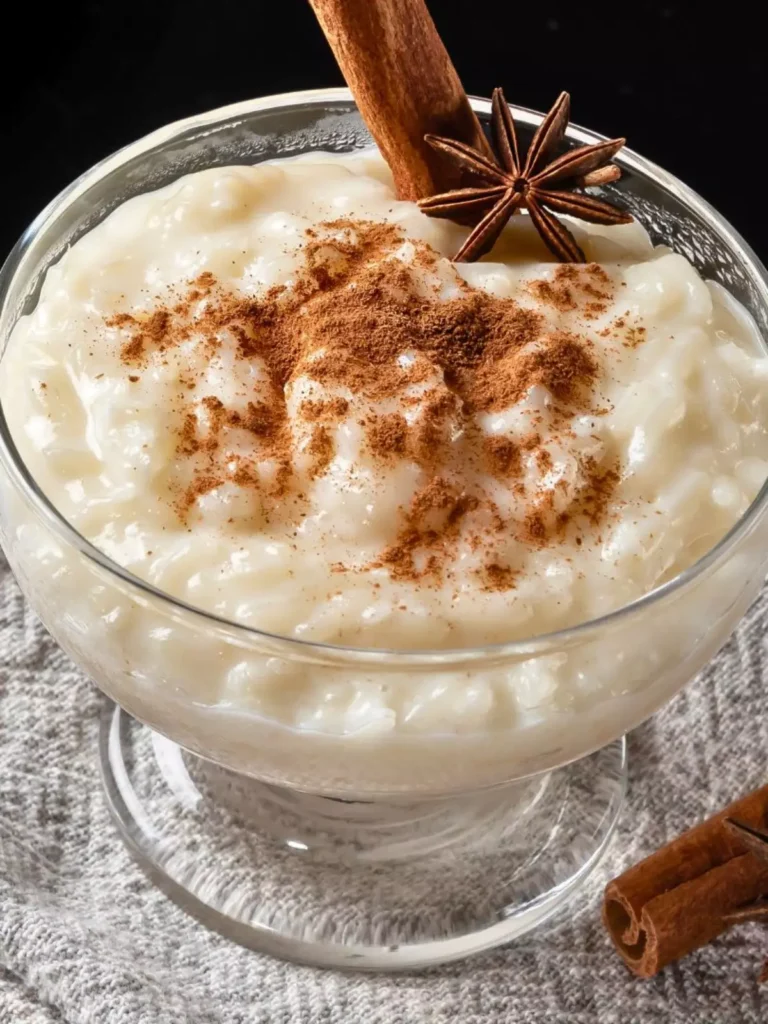 Tigela de arroz doce cremoso, polvilhado com canela em pó e decorado com um pau de canela.