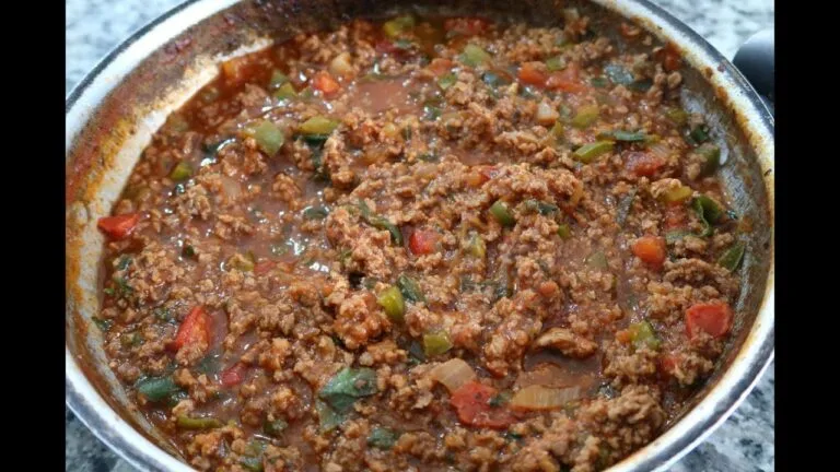 Carne moída sendo preparada em uma frigideira, com textura dourada e uniformemente cozida.