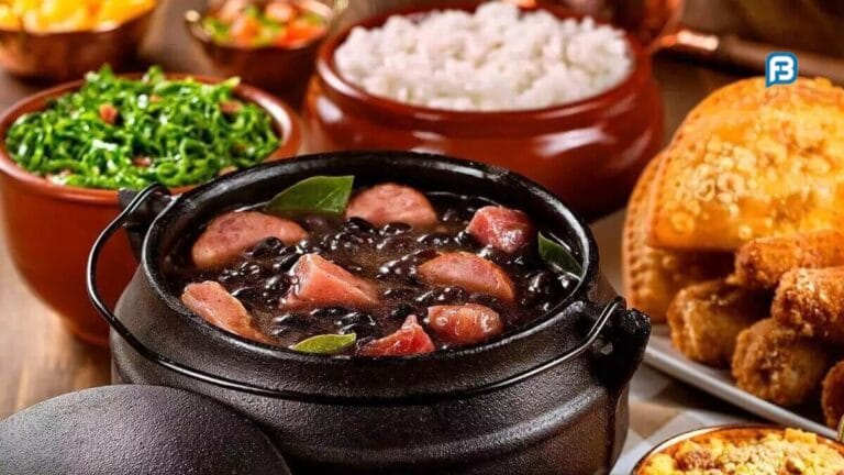 Panela grande de feijoada com carnes variadas, servida com arroz, couve, farofa e laranja.