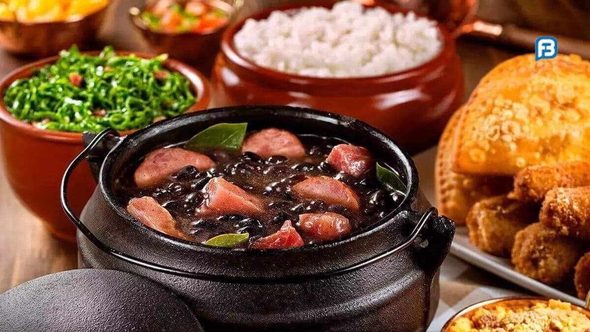 Panela grande de feijoada com carnes variadas, servida com arroz, couve, farofa e laranja.