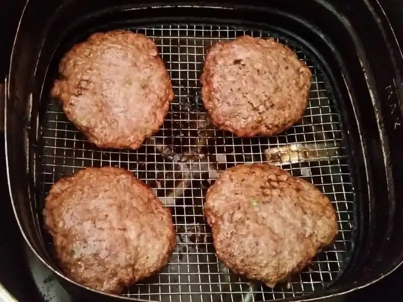 Hambúrguer caseiro sendo assado na airfryer a 180°C, com a carne dourada e suculenta.