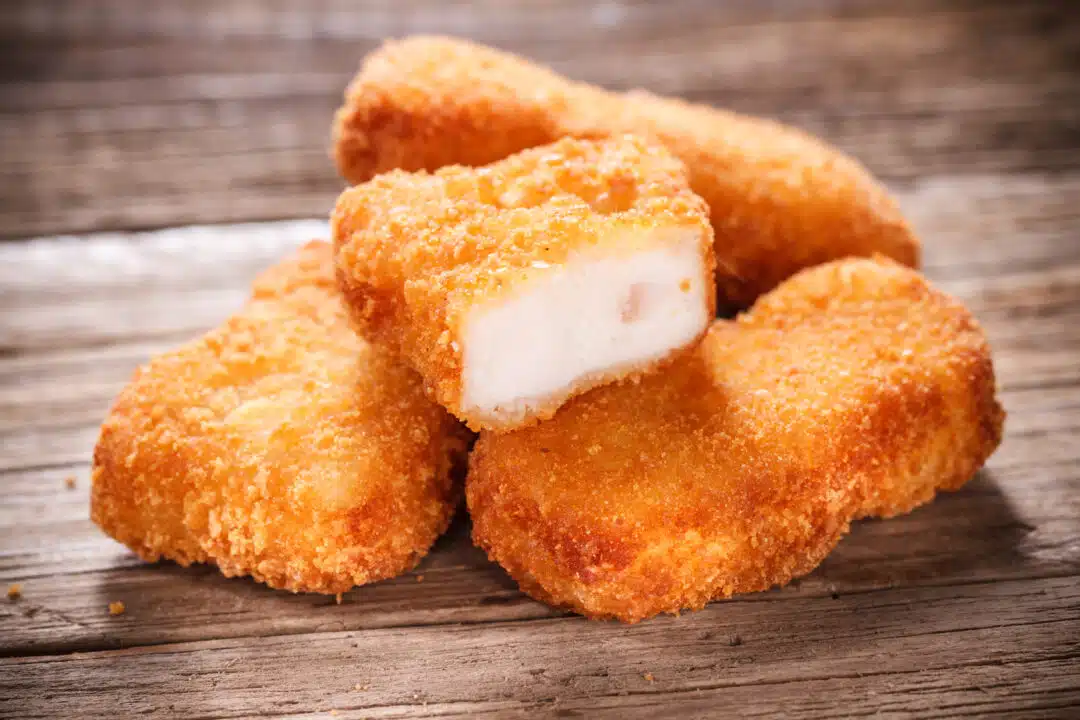 Nuggets de frango assando no forno a 200°C, com crosta dourada e crocante.