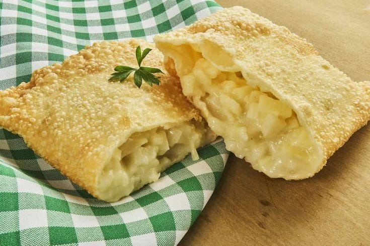 Tigela com recheio de palmito cremoso para pastel, com pedaços de palmito visíveis e cheiro-verde picado por cima.