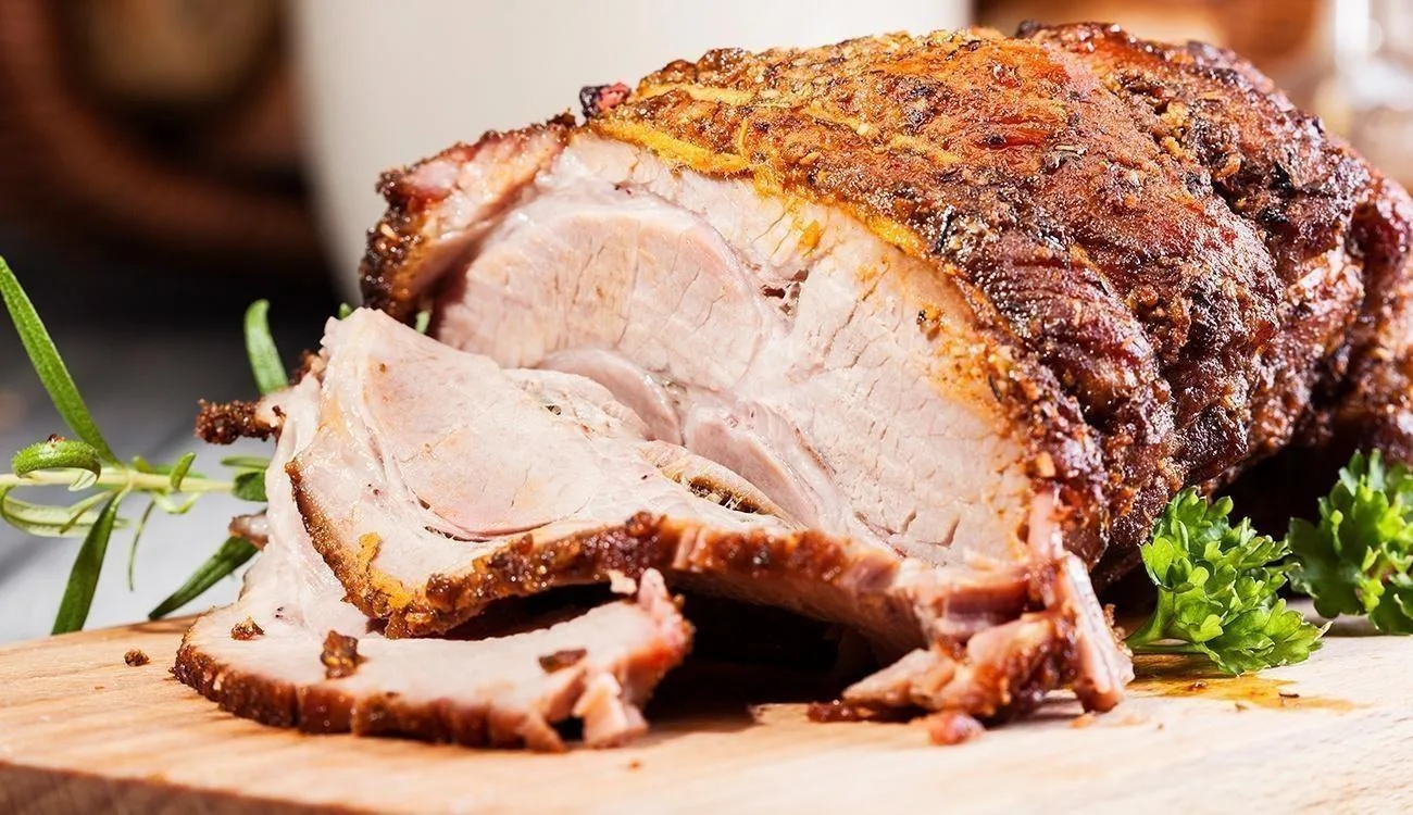 Picanha suína assada no forno, fatiada e servida com farofa e vinagrete.