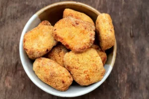 Nuggets caseiros crocantes e dourados, prontos para servir com molho de ketchup.