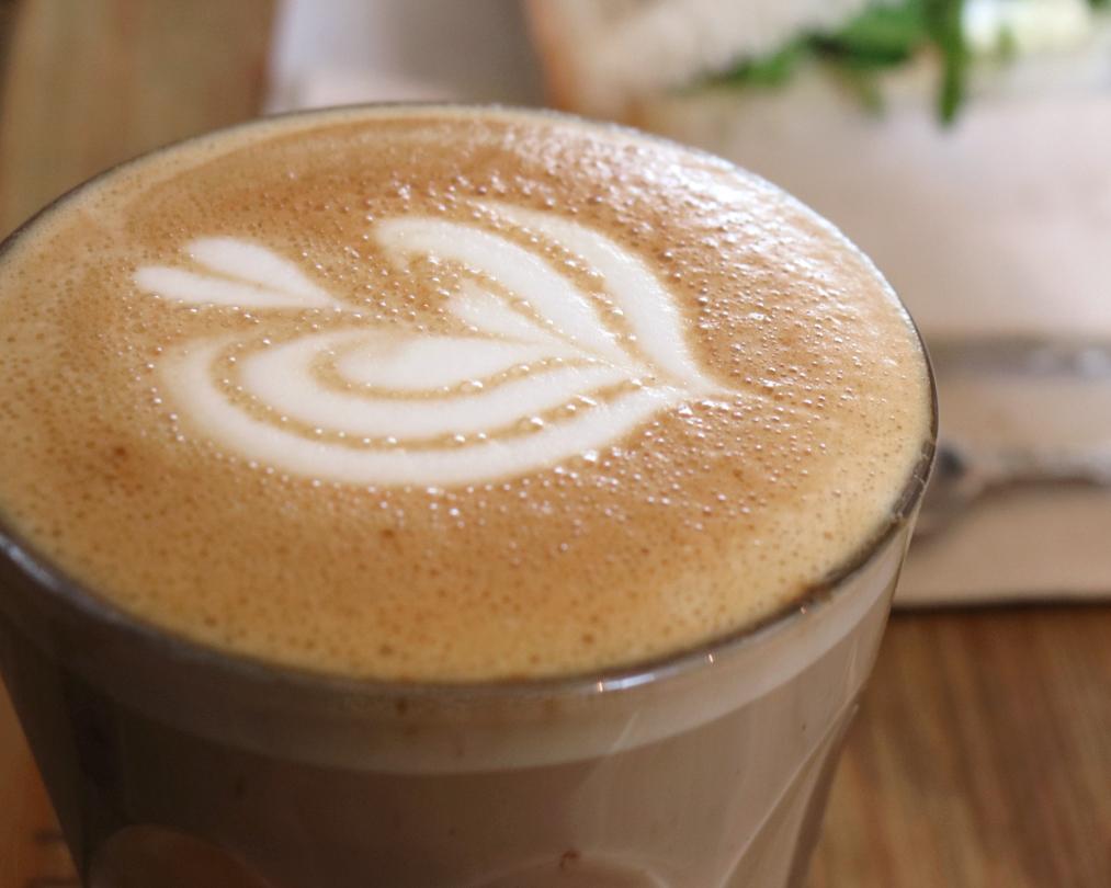 Xícara de cappuccino cremoso com espuma de leite por cima, polvilhado com cacau em pó.