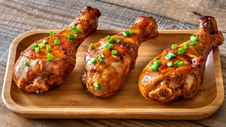 Coxas de frango temperadas sendo colocadas na cesta da airfryer.