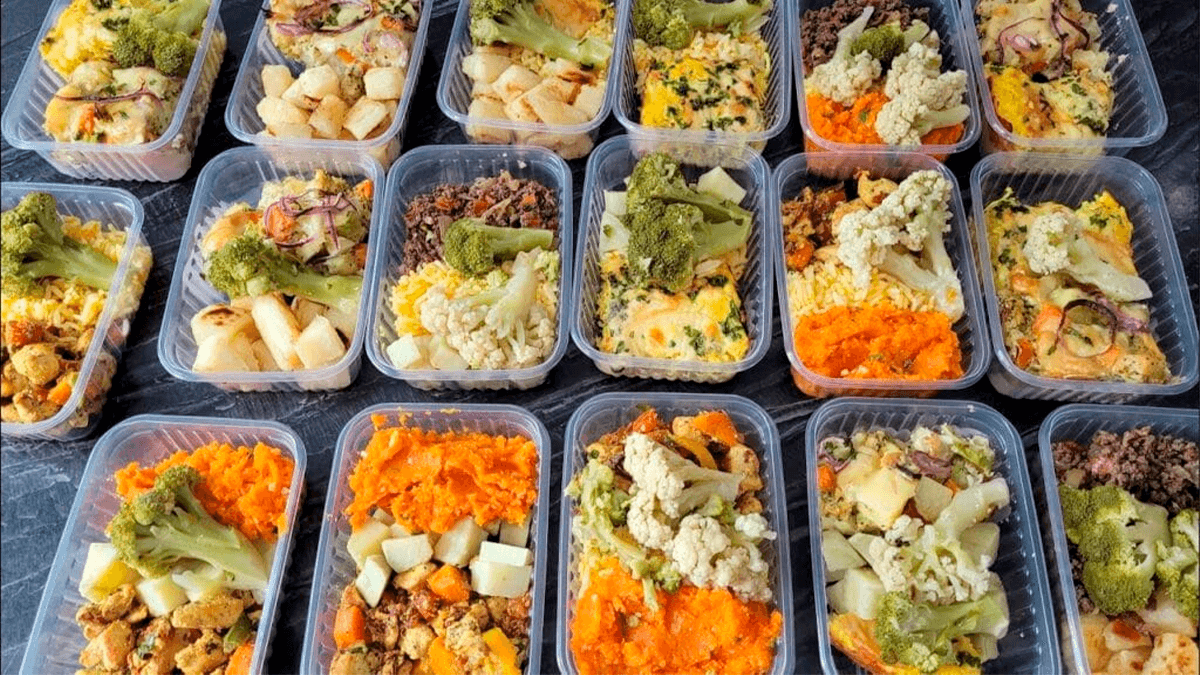 Uma marmita fit colorida e organizada, com os 4 grupos de alimentos destacados: proteína magra, carboidratos complexos, legumes e vegetais, e gorduras boas.