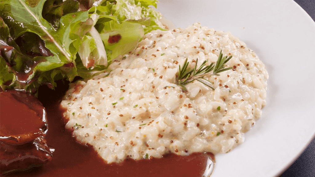 Um prato de arroz à piamontese cremoso, servido ao lado de um bife grelhado, representando uma das combinações sugeridas no artigo.