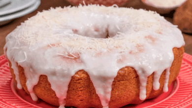 Bolo de coco fofinho com calda cremosa de coco escorrendo, coco ralado polvilhado por cima.