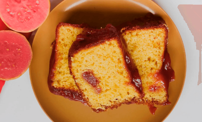 Foto apetitosa de um bolo de goiaba fresca de liquidificador recém-assado e fofinho, decorado com goiabas frescas e açúcar de confeiteiro.