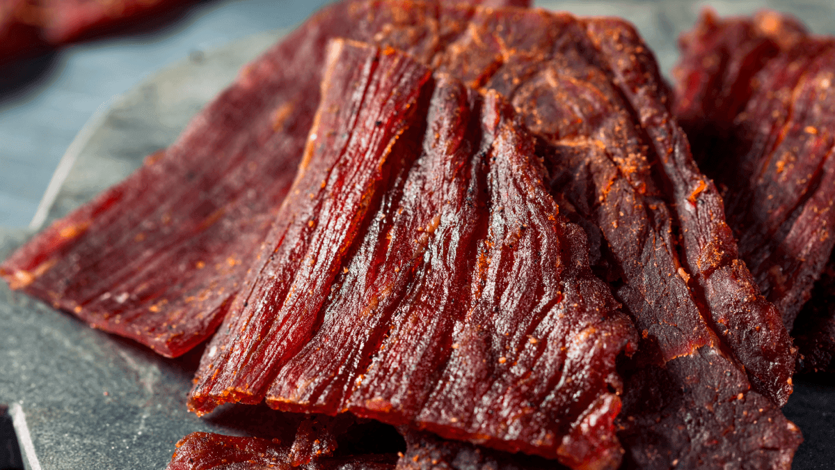 Pedaços de carne de sol sendo dessalgados em uma tigela com água, representando o processo de dessalgue ensinado no artigo.