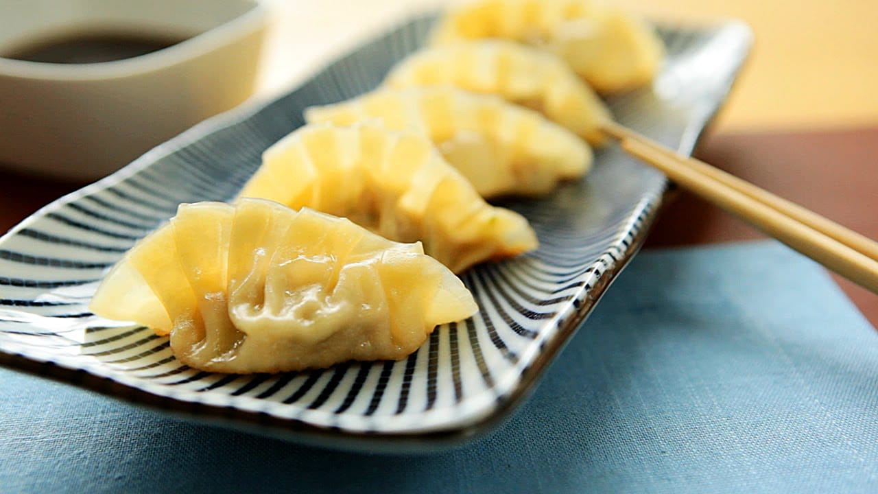 Gyozas dourados e crocantes, servidos em um prato com molho para mergulhar.