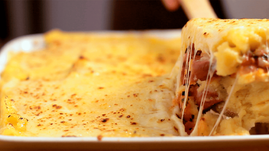 Refratário com polenta cremosa queijo forno gratinada, destacando a casquinha dourada e o queijo derretido.