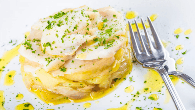 Bacalhau assado no forno, com batatas douradas e azeitonas, pronto para servir.