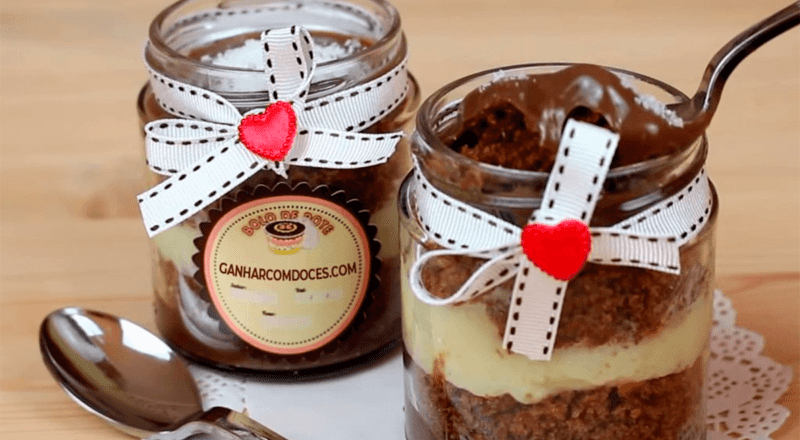 Diversos bolos no pote, com diferentes sabores e coberturas, arrumados em uma mesa, representando a variedade e a atratividade do produto, além do potencial lucrativo do negócio.