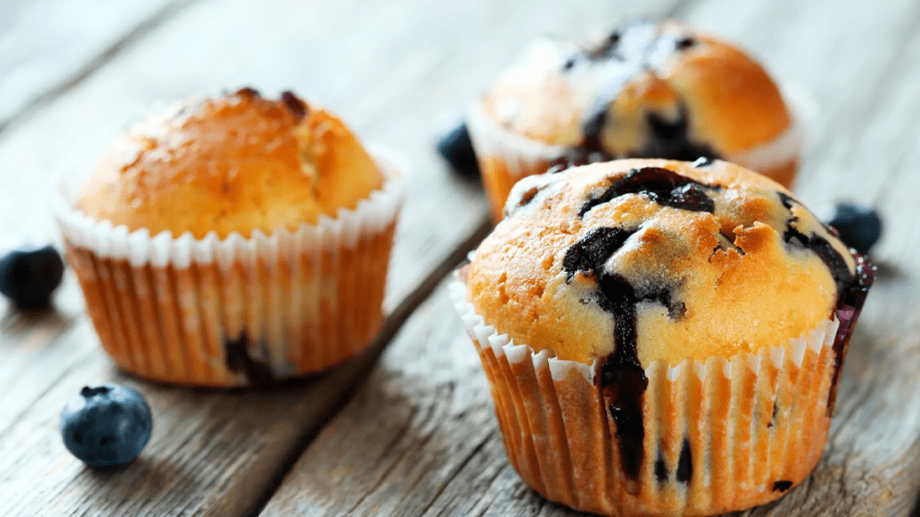 Muffins de amora com farofa crocante em uma cesta, com amoras frescas espalhadas ao redor.