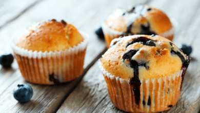 Muffins de amora com farofa crocante em uma cesta, com amoras frescas espalhadas ao redor.