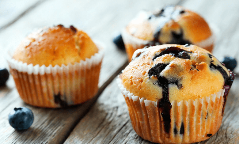 Muffins de amora com farofa crocante em uma cesta, com amoras frescas espalhadas ao redor.