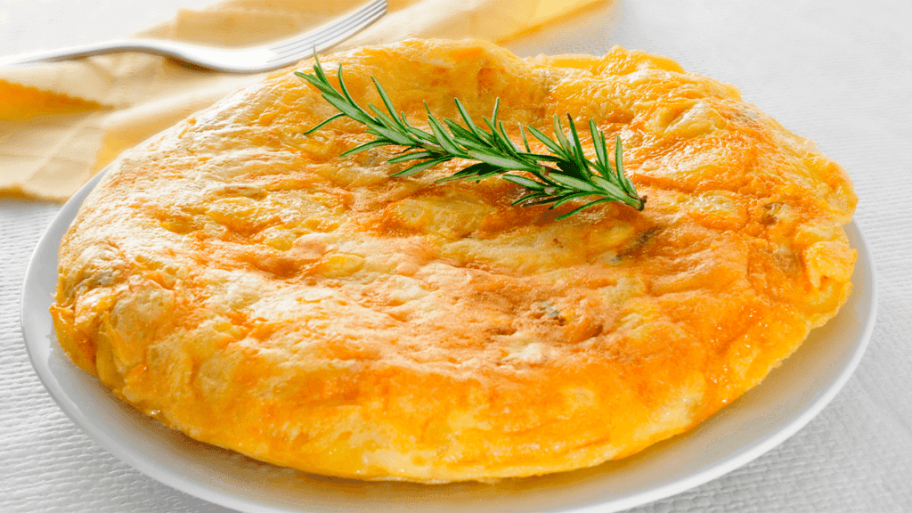 Omelete fofinho e dourado sendo preparado em uma frigideira