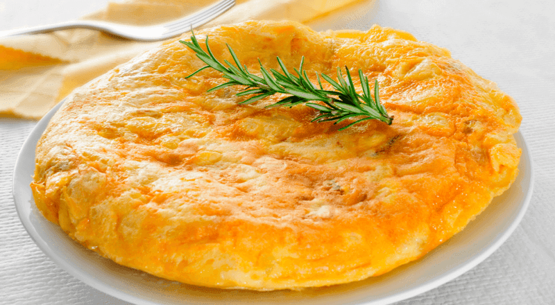 Omelete fofinho e dourado sendo preparado em uma frigideira