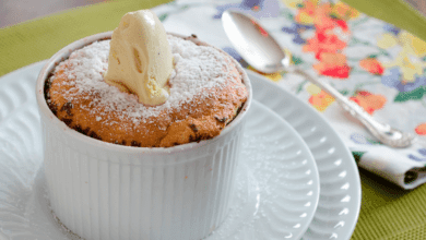 Suflê de pistache caseiro, recém-saído do forno, em refratário individual, polvilhado com açúcar de confeiteiro e decorado com pistaches.