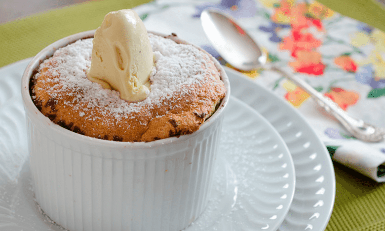 Suflê de pistache caseiro, recém-saído do forno, em refratário individual, polvilhado com açúcar de confeiteiro e decorado com pistaches.