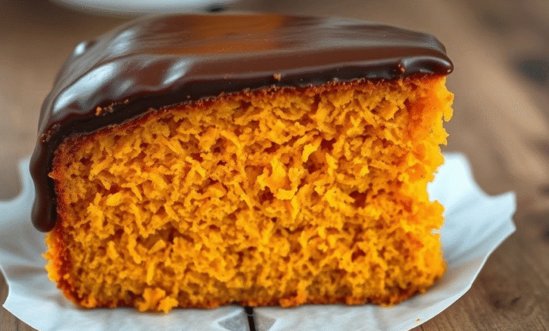 Fatia generosa de Bolo de Cenoura de Todo Dia, fofinho e alaranjado, com cobertura brilhante de chocolate escorrendo, em um prato branco.