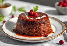 O bolo pudim de chocolate pronto, com camadas visíveis de pudim e bolo, coberto por calda dourada brilhante em um prato elegante
