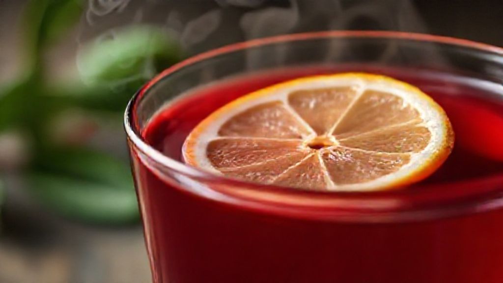 Close-up da xícara de chá detox finalizada, destacando cor rubi intensa e detalhes aromáticos.