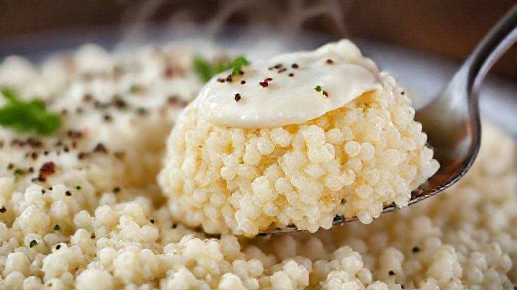 Close-up da fatia de cuscuz de tapioca servida no prato, mostrando textura macia e cobertura com leite condensado.