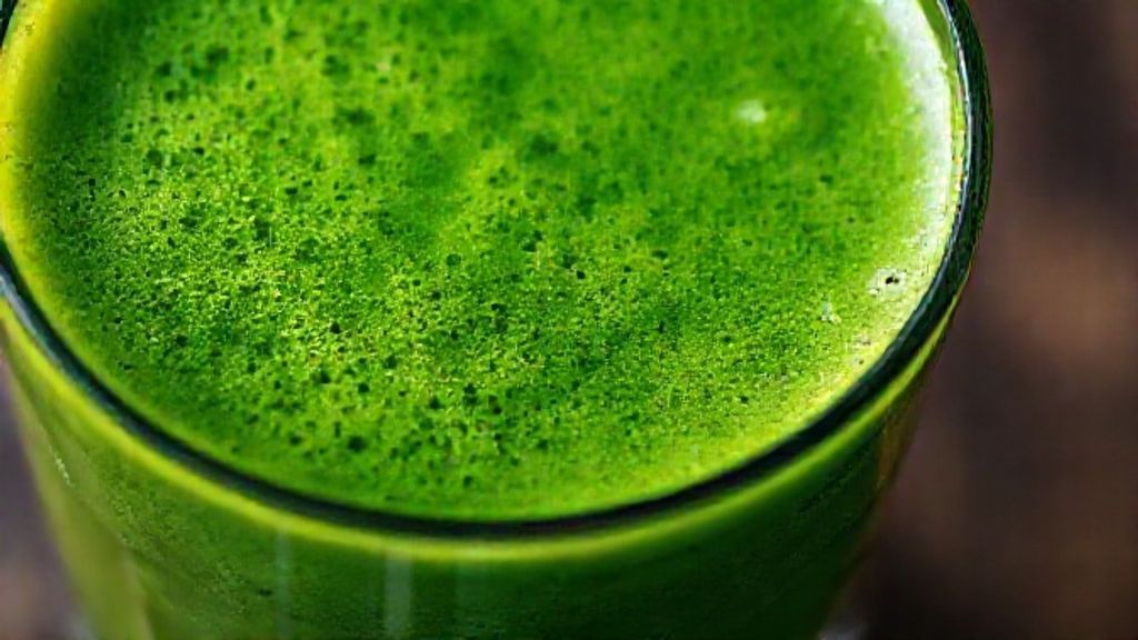 Close-up do suco verde detox termogênico em copo transparente, destacando a textura fresca e vibrante