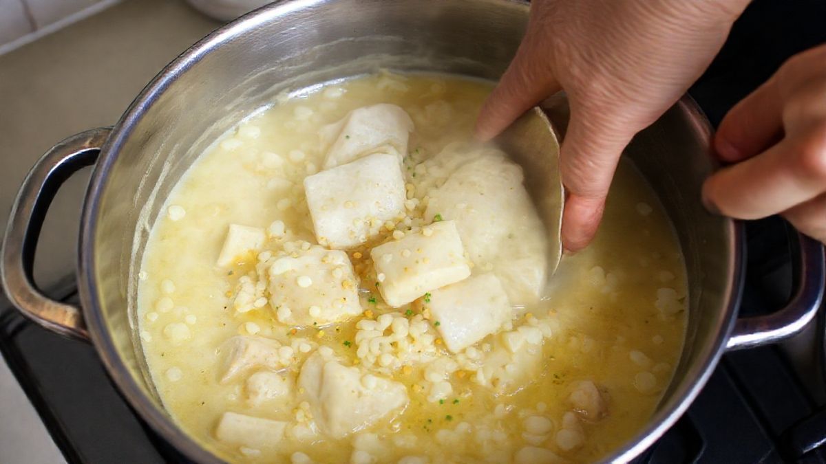 Mãos mexendo panela durante o refogado do bacalhau com cebola e alho