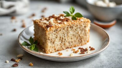 Bolo de coco com farinha de aveia dourado e úmido, coberto com coco ralado, servido em prato de porcelana sobre mesa rústica