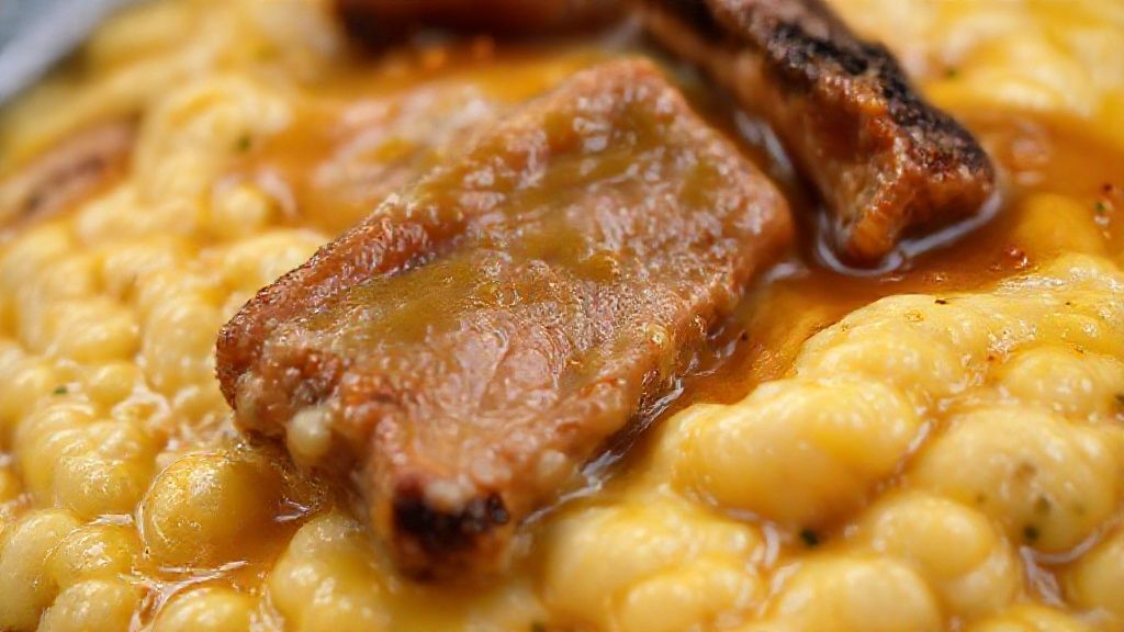 Close-up da canjiquinha cremosa com pedaços de costelinha dourada e couve fresquinha por cima