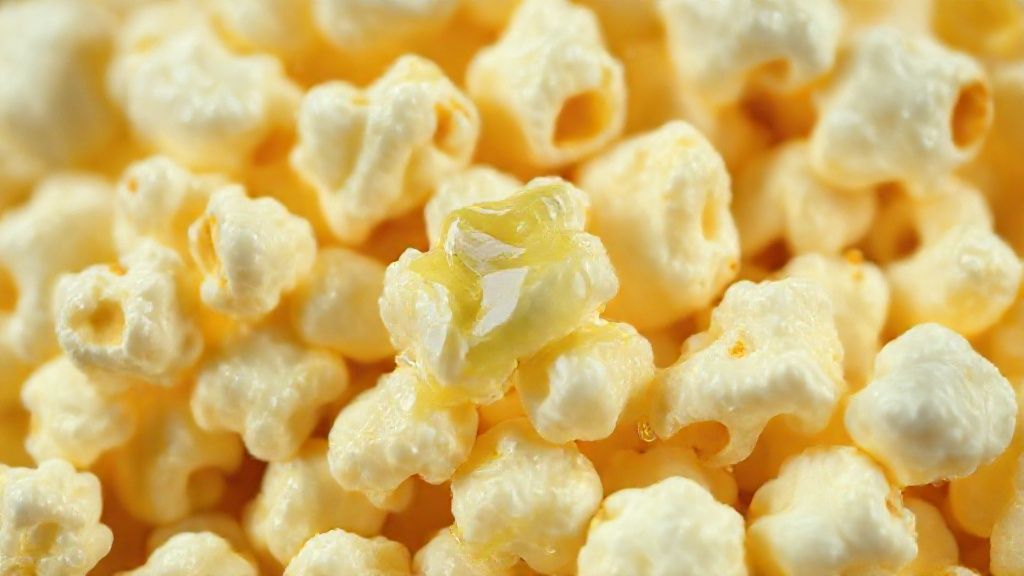 Close-up das pipocas crocantes com brilho da manteiga derretida destacando textura e cor dourada