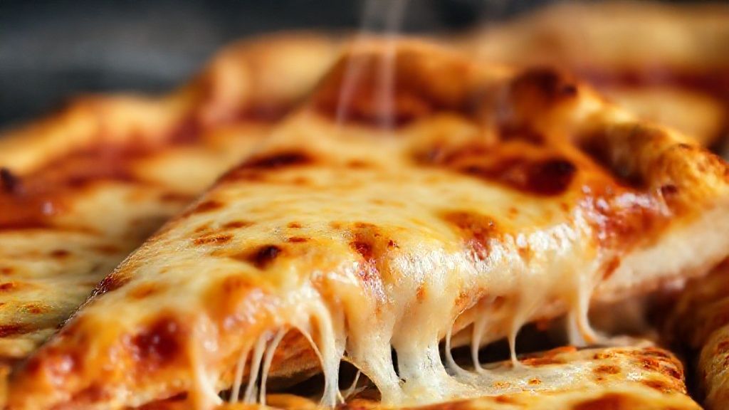 Close-up de fatia de pizza reaquecida, com queijo derretendo e borda crocante.