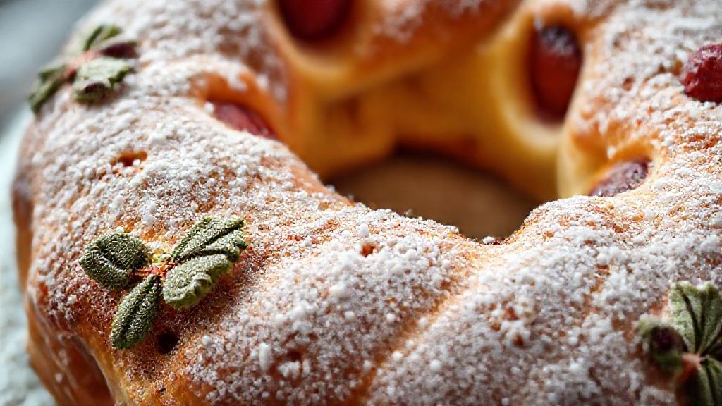 Close-up da rosca doce de Natal finalizada, mostrando a textura macia e as frutas cristalizadas no topo