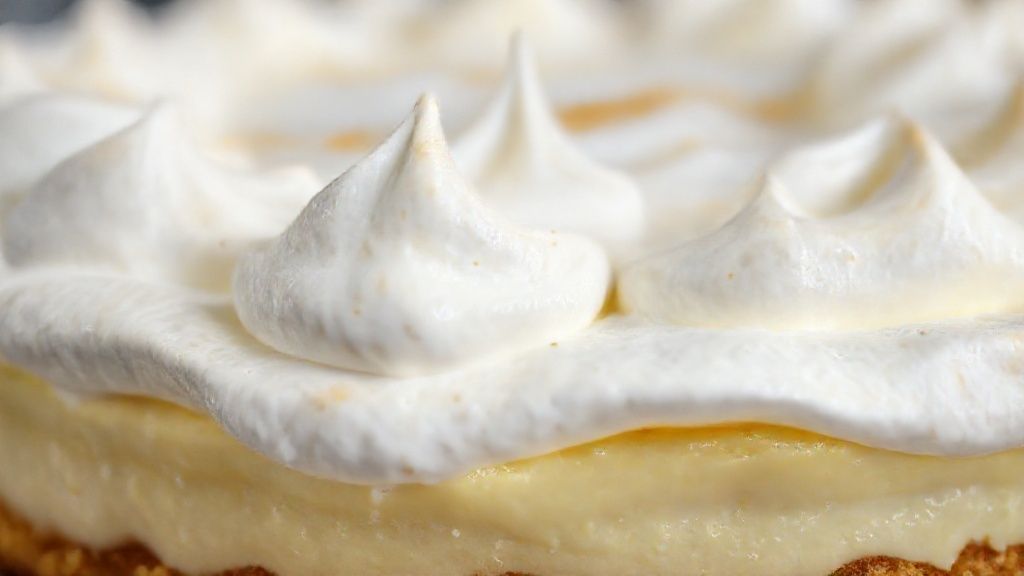 Close-up da fatia de torta de limão mostrando camadas cremosas e o brilho do merengue