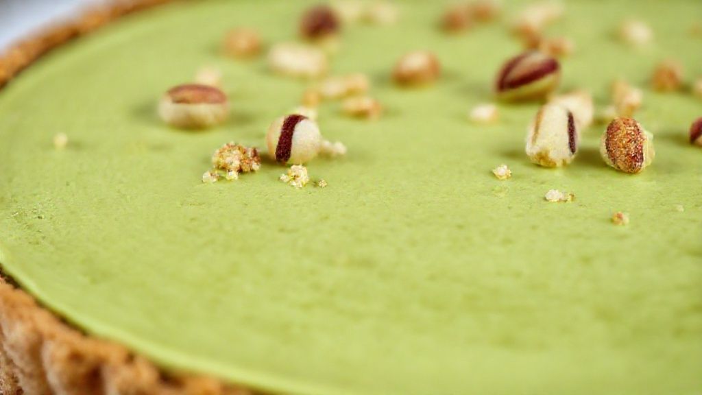 Close-up do corte da torta mostrando camadas do creme de pistache e base crocante