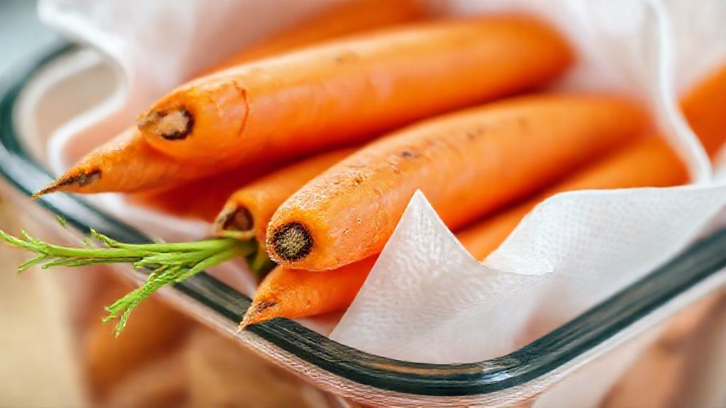 Close-up da textura das cenouras armazenadas em pote de vidro com papel-toalha.