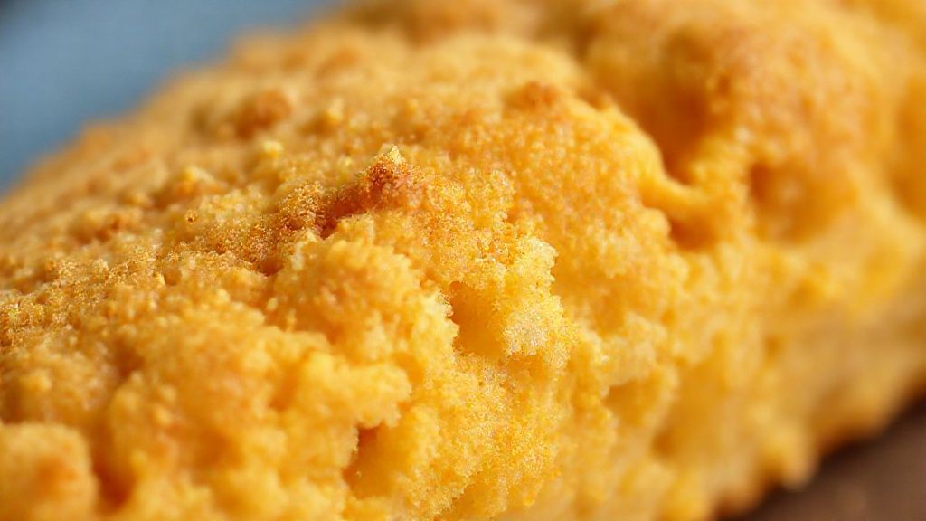 Close-up do biscoito de polvilho crocante mostrando textura aerada e dourada