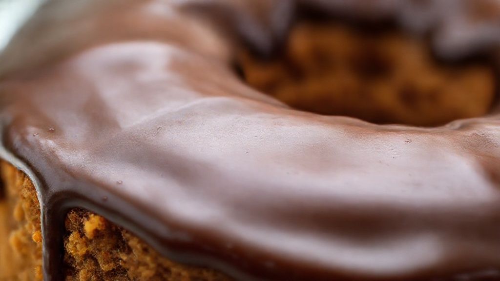 Close-up do bolo de cenoura sem açúcar cortado, mostrando sua textura fofa e cobertura brilhante de chocolate
