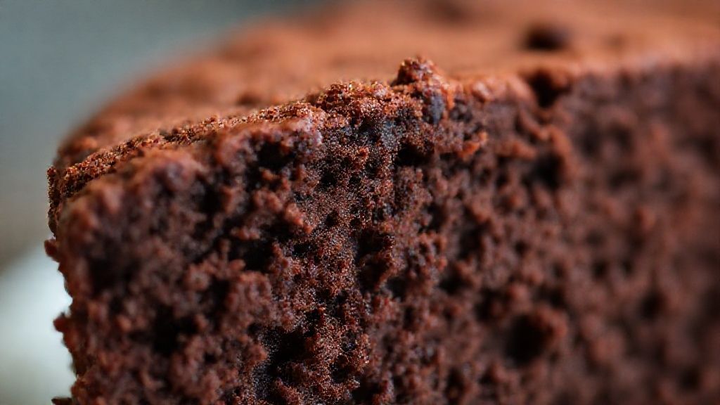 Close-up do bolo de chocolate cortado, mostrando interior úmido e textura leve