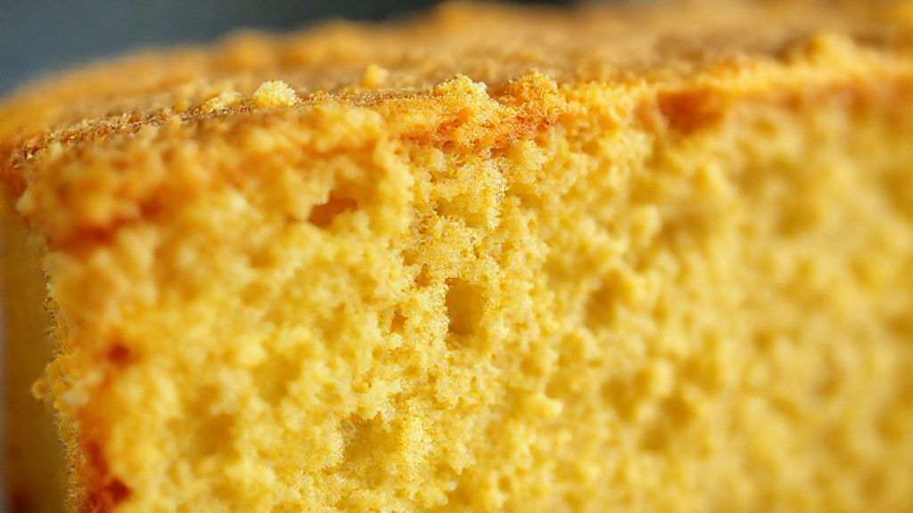 Close-up do bolo de fubá cremoso dourado mostrando textura úmida e camada cremosa