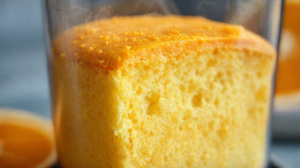 Close-up do bolo de laranja fofo cortado, mostrando a textura úmida e a calda brilhante