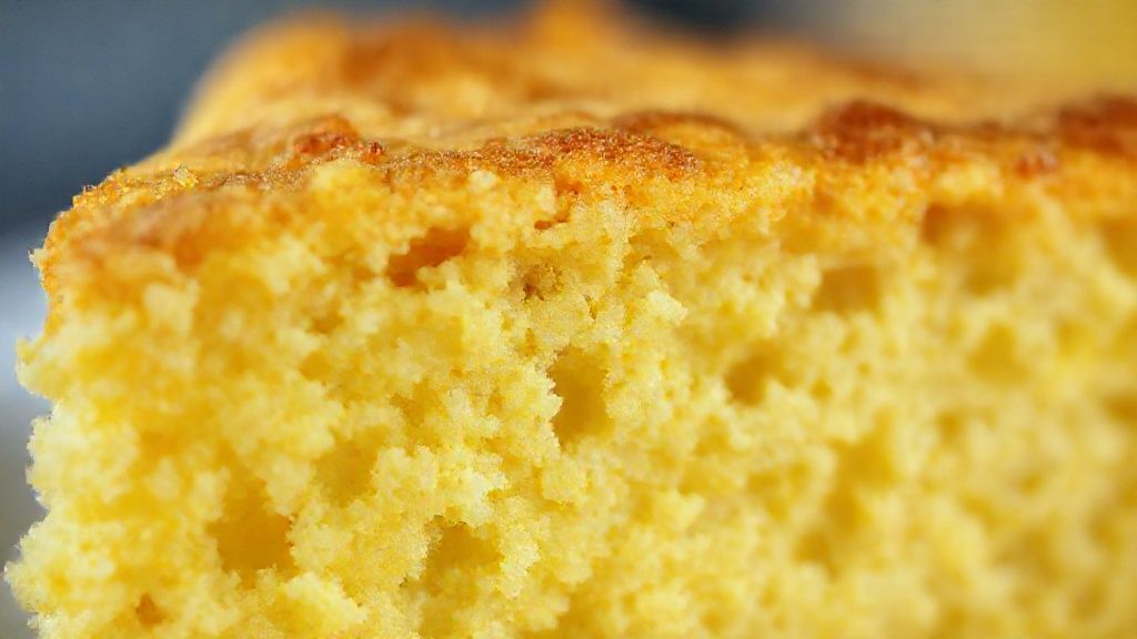 Close-up da fatia do bolo mostrando textura cremosa e crosta dourada