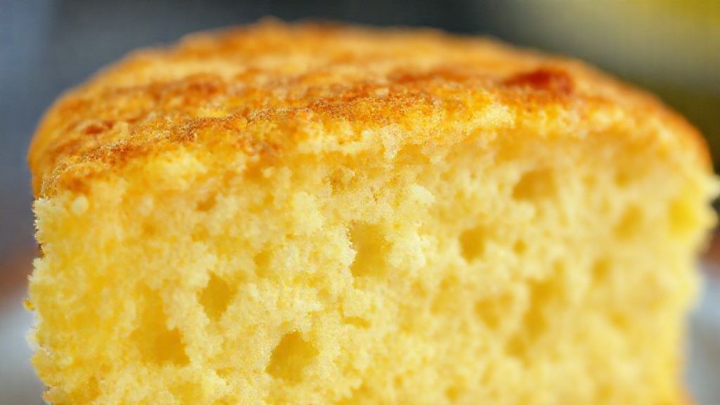 Close-up do bolo cortado mostrando a textura fofa e dourada por dentro