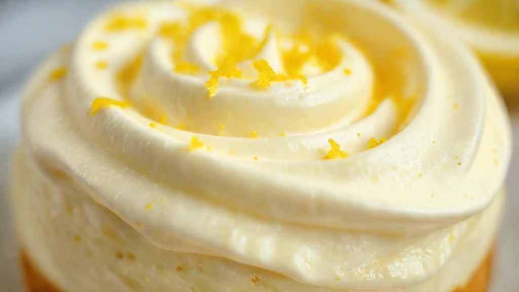Close-up do cremosão de limão pronto, destacando a textura cremosa e brilhante com raspas de limão por cima
