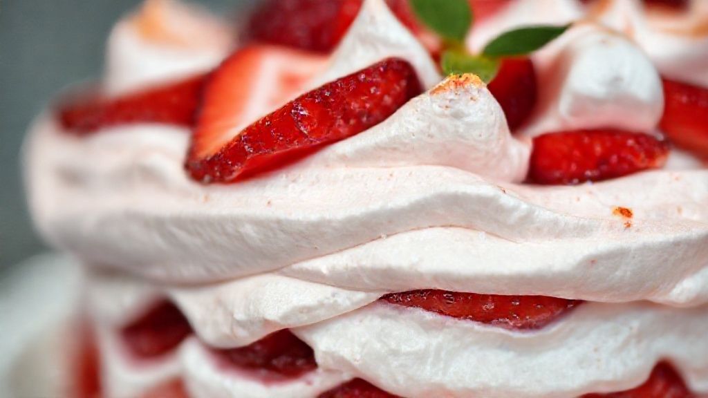 Close-up mostrando camadas do doce com morangos, suspiro e chantilly